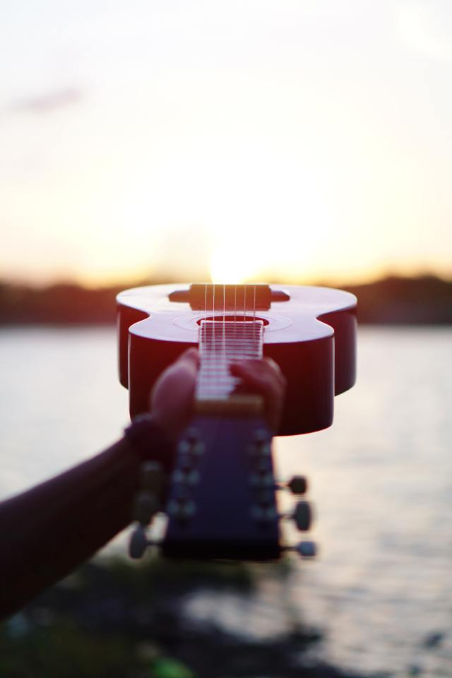 Close-up of a classical acoustic guitar resting against a wall